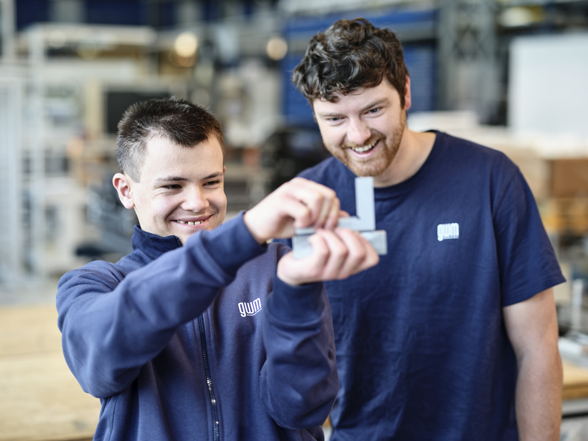 Lehrling und Ausbildner in der Fertigung prüfen ein Element