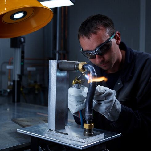 Industriemitarbeiter beim präzisen Hartlöten von Kupfer-Edelstahl-Verbindungen