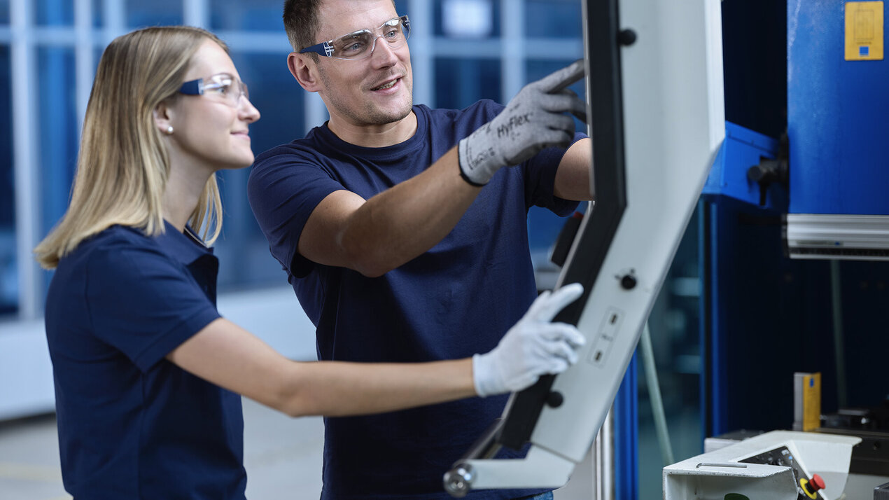 Ausbilder erklärt einem Lehrling einen Arbeitsschritt am Bildschirm